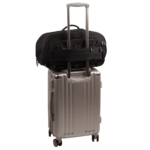 back view of compact, black pet car seat sitting on a silver, hardshell suitcase, secured with the carrier's trolley sleeve - view 7