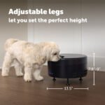 Dog interacting with a black pet feeder on a wooden floor, with text about adjustable legs.